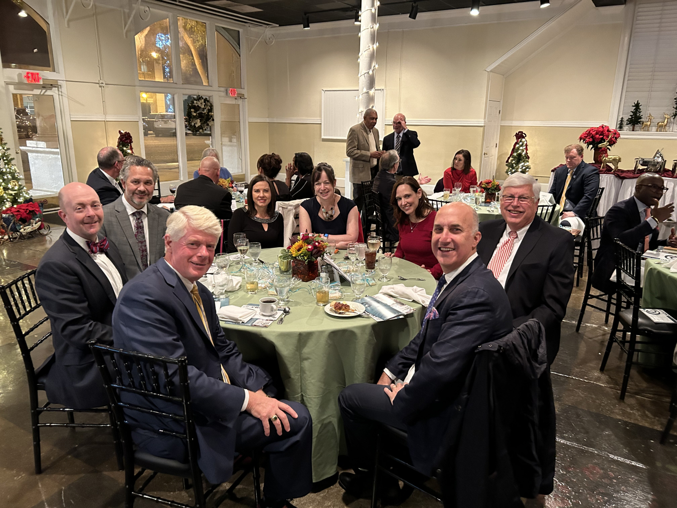 A group of people sit around a round table while smiling for the picture