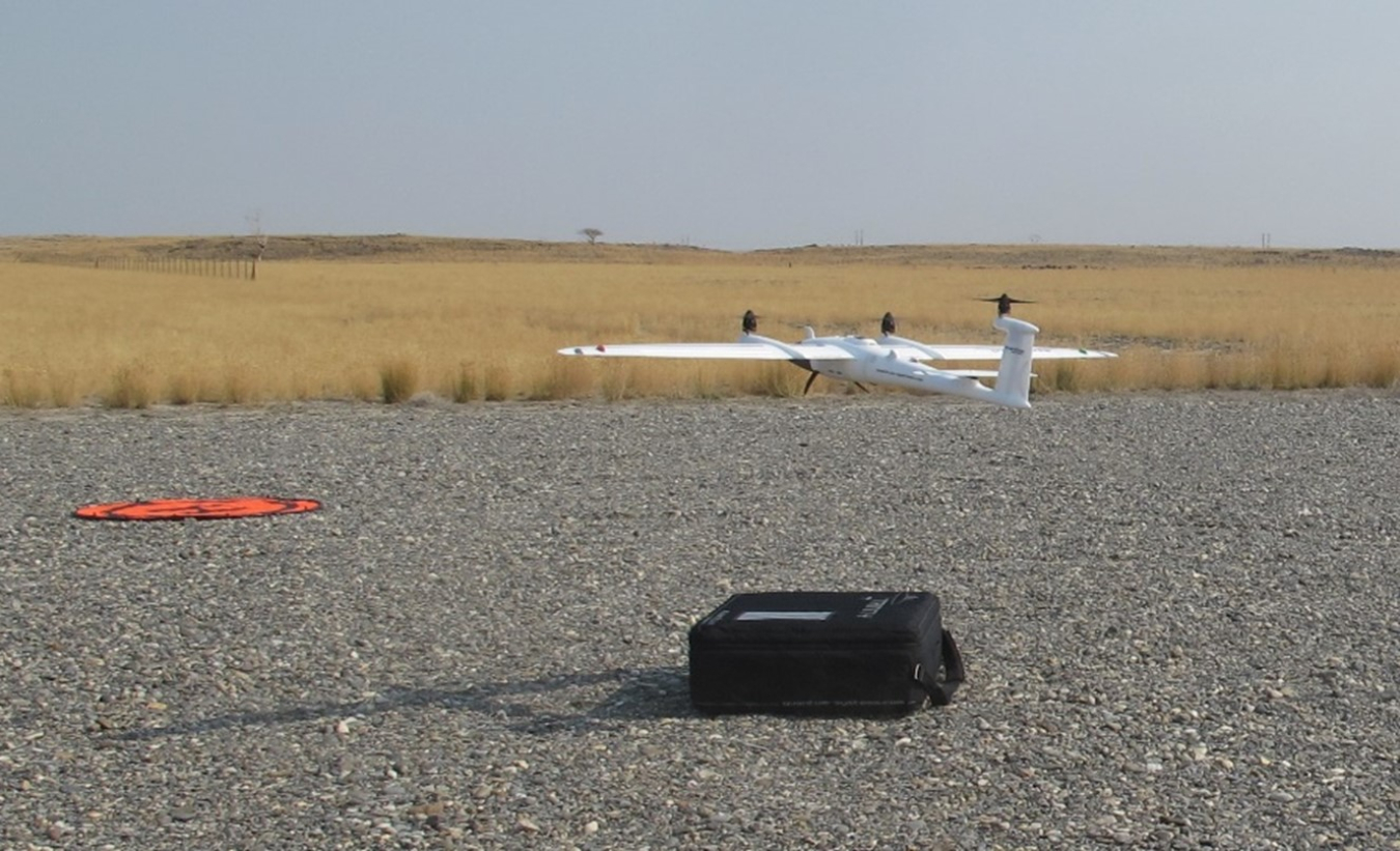 A drone takes flight off the gravel ground