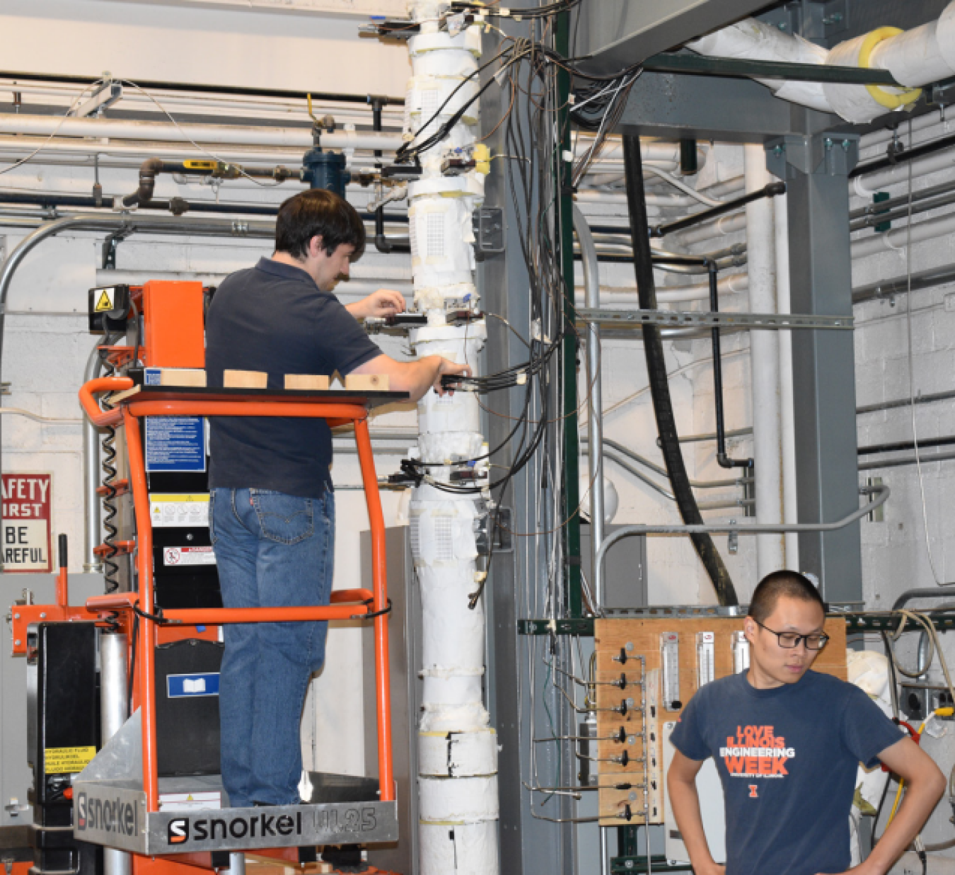 Two men in laboratory, one on lift and one standing on ground