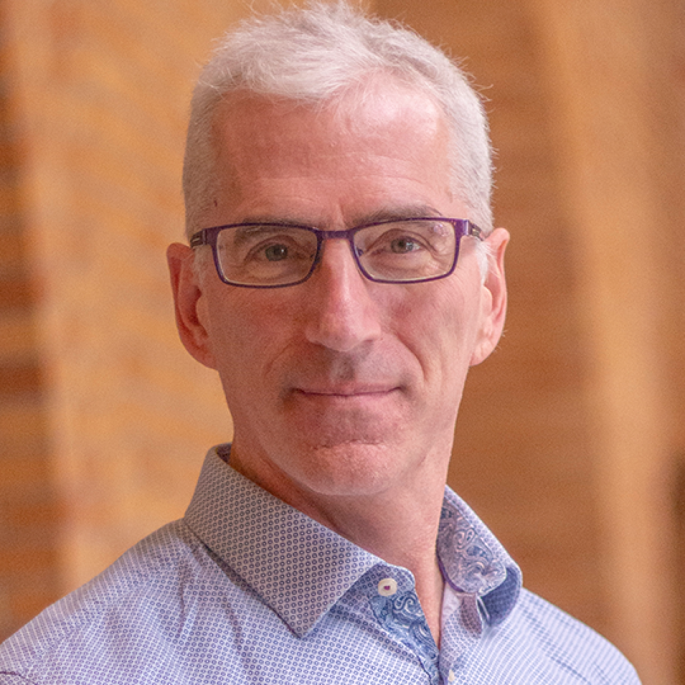 Joel Ager, smiling and wearing glasses and a collared shirt