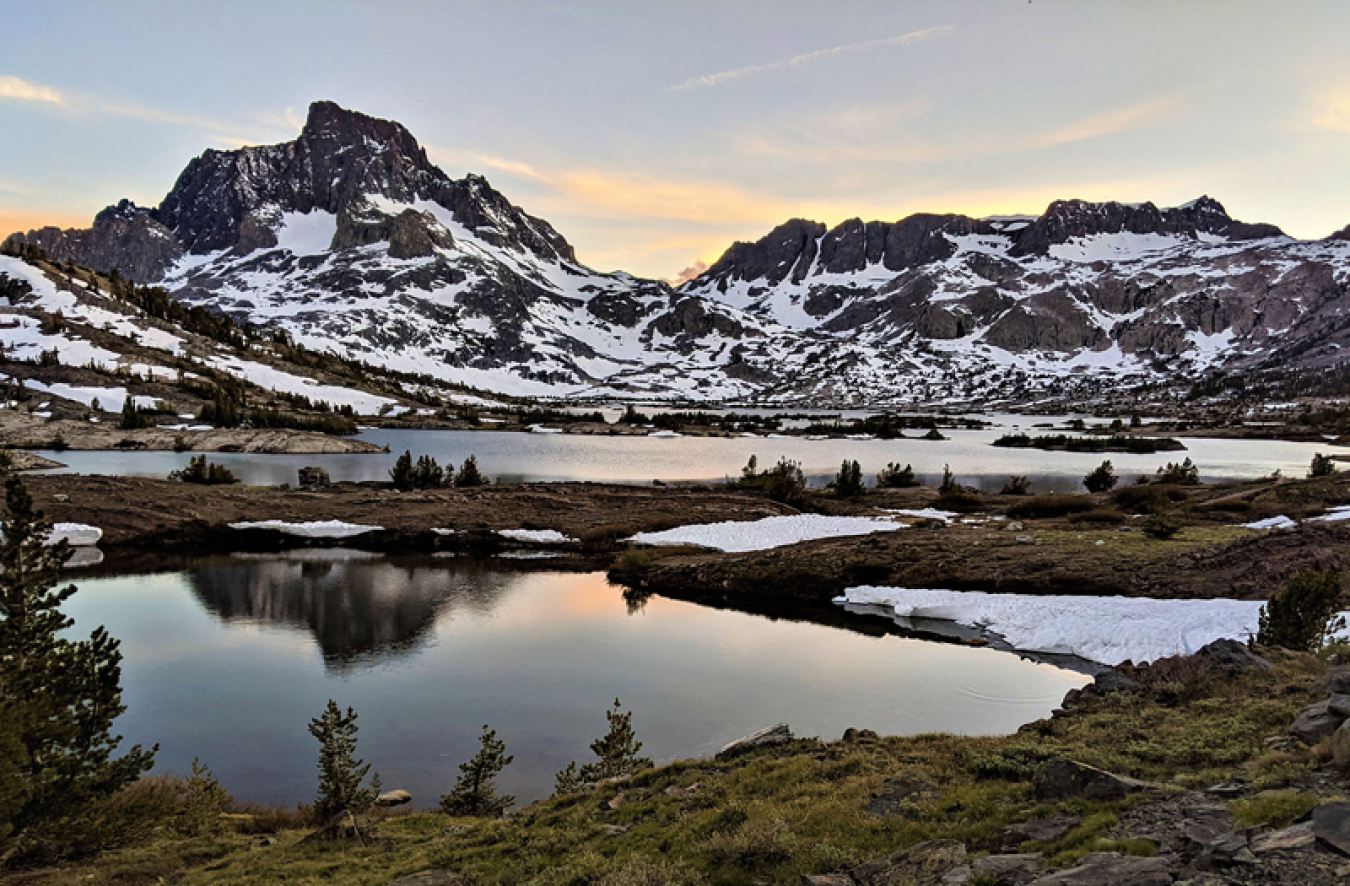 Snow on mountains, with lakes and ponds in front of the mountains.