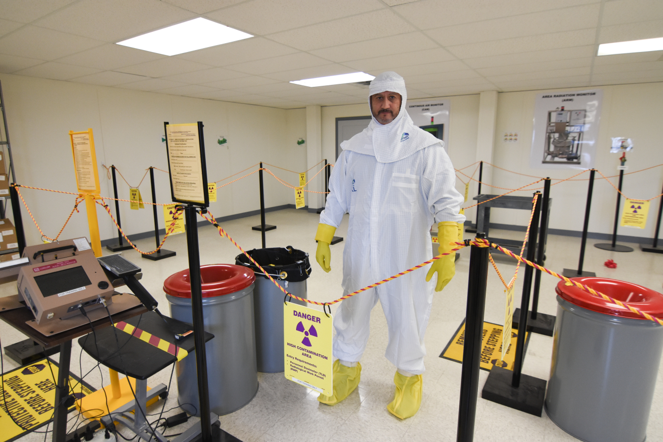 A man in a white hazmat suit stands in the middle of a training setup 