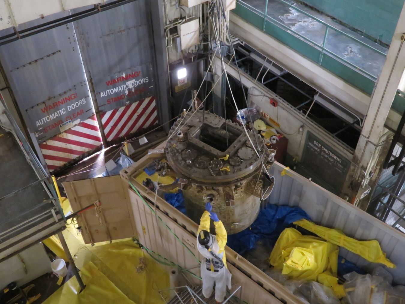 Workers removing parts of a large piece of equipment 