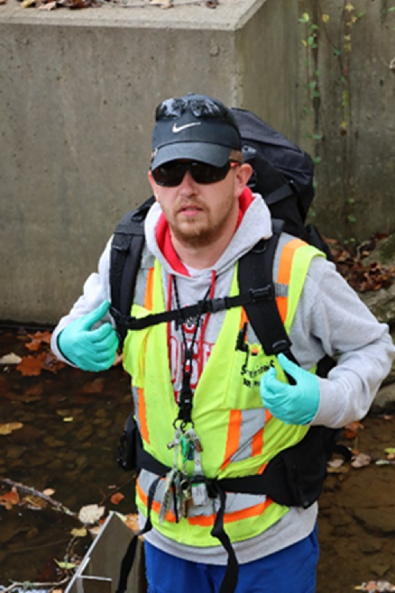 A man in a neon yellow safety vest with a bookbag on carry equiptment