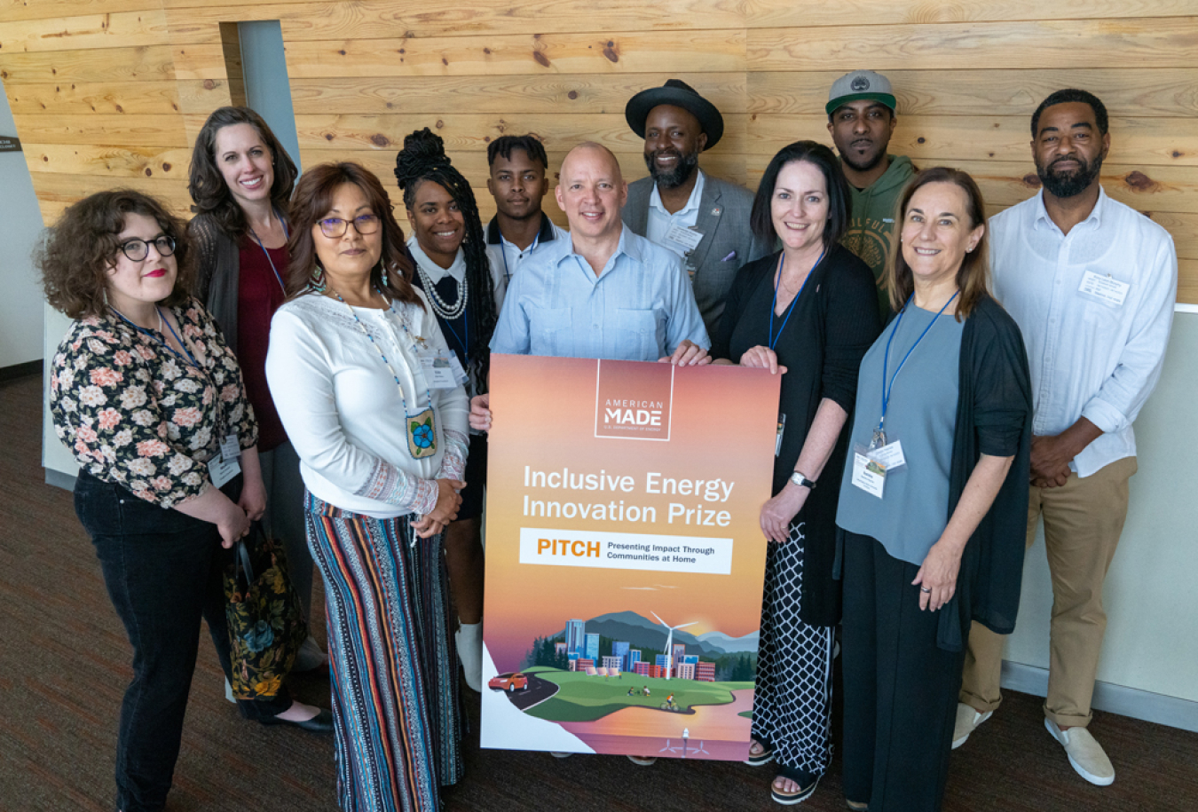 Eleven people standing behind a poster-sized sign for the Inclusive Energy Innovation Prize