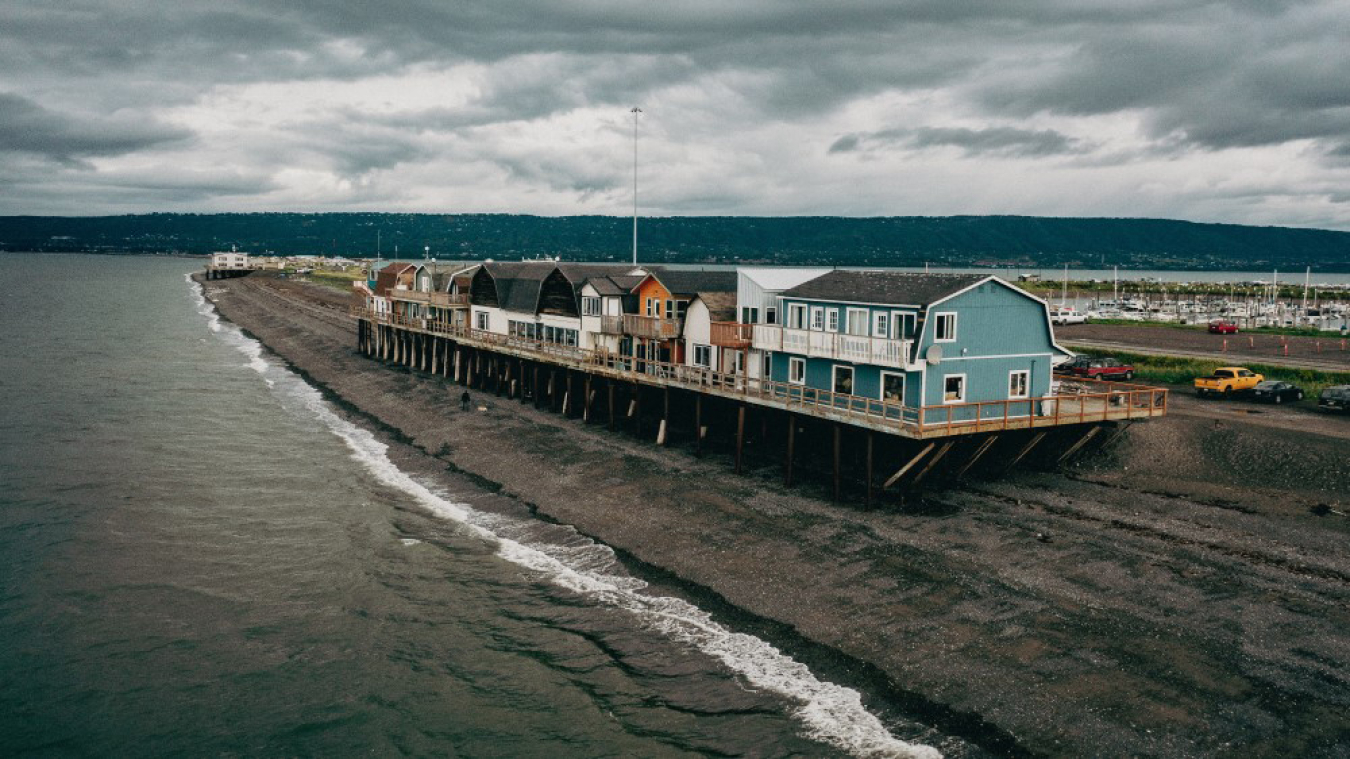 A row of houses built on a platform next to a shoreline