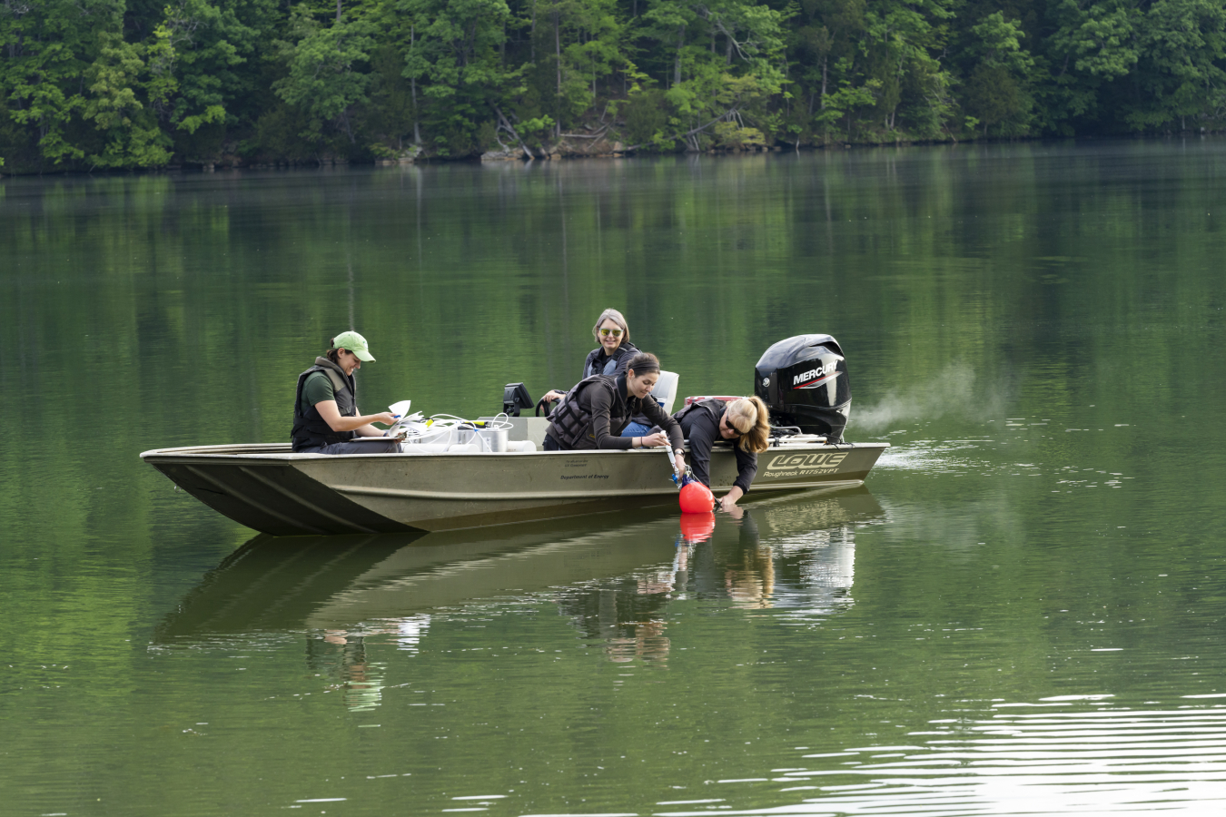 scientists in a motorboat measure greenhouse gas emissions from a reservoir