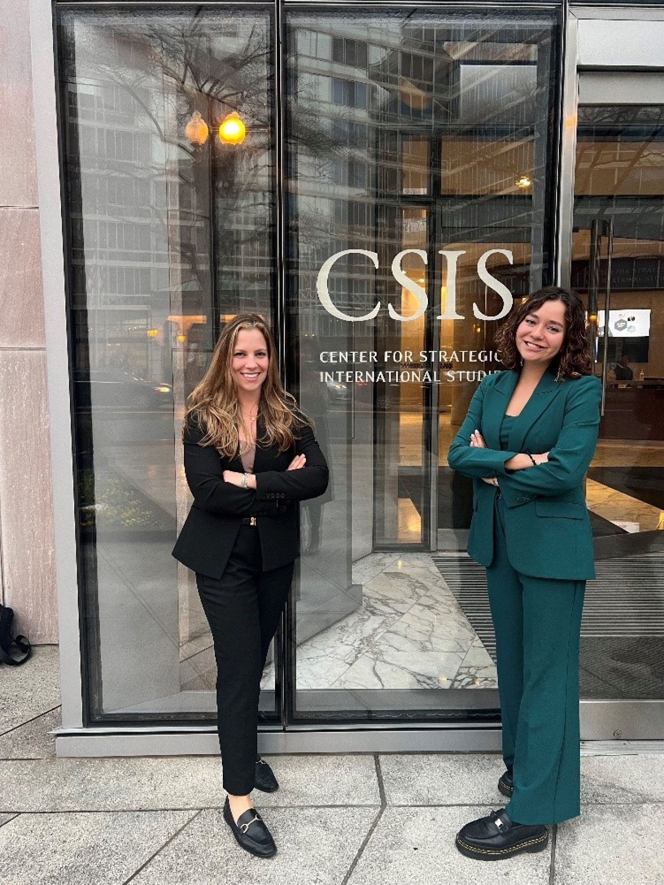 Two women standing on either side of a metal door whose signage reads "CSIS Center for Strategic International Studies"