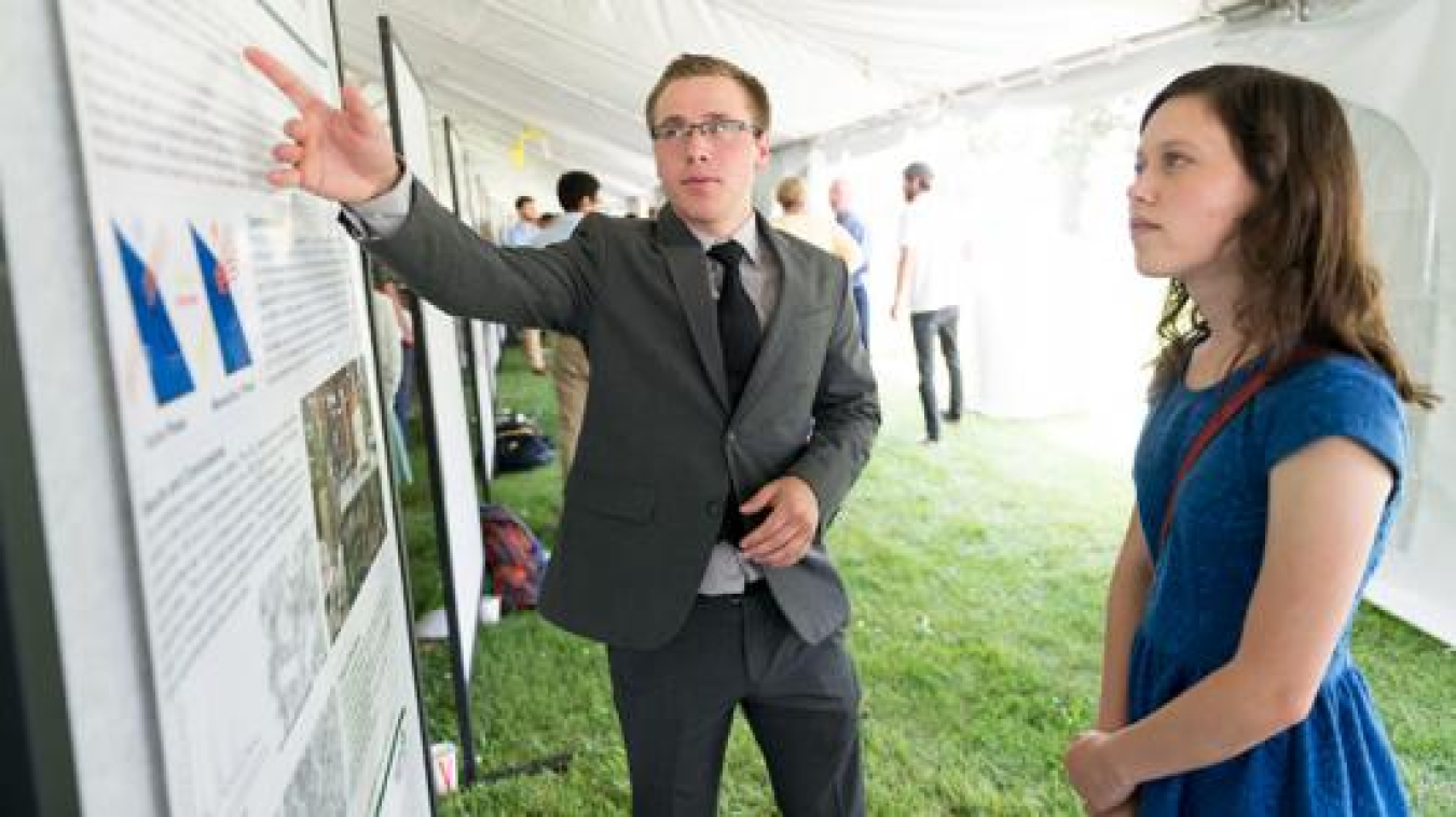 William Trevillyan discussing his research poster with fellow intern.