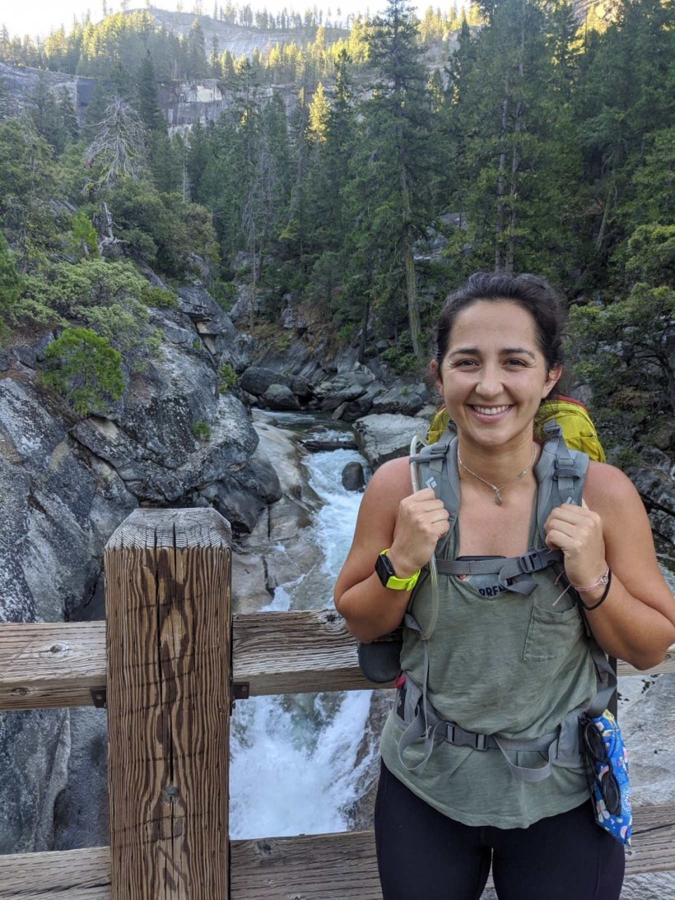 Claire Gonzales standing on a bridge above a river wearing a backpack.