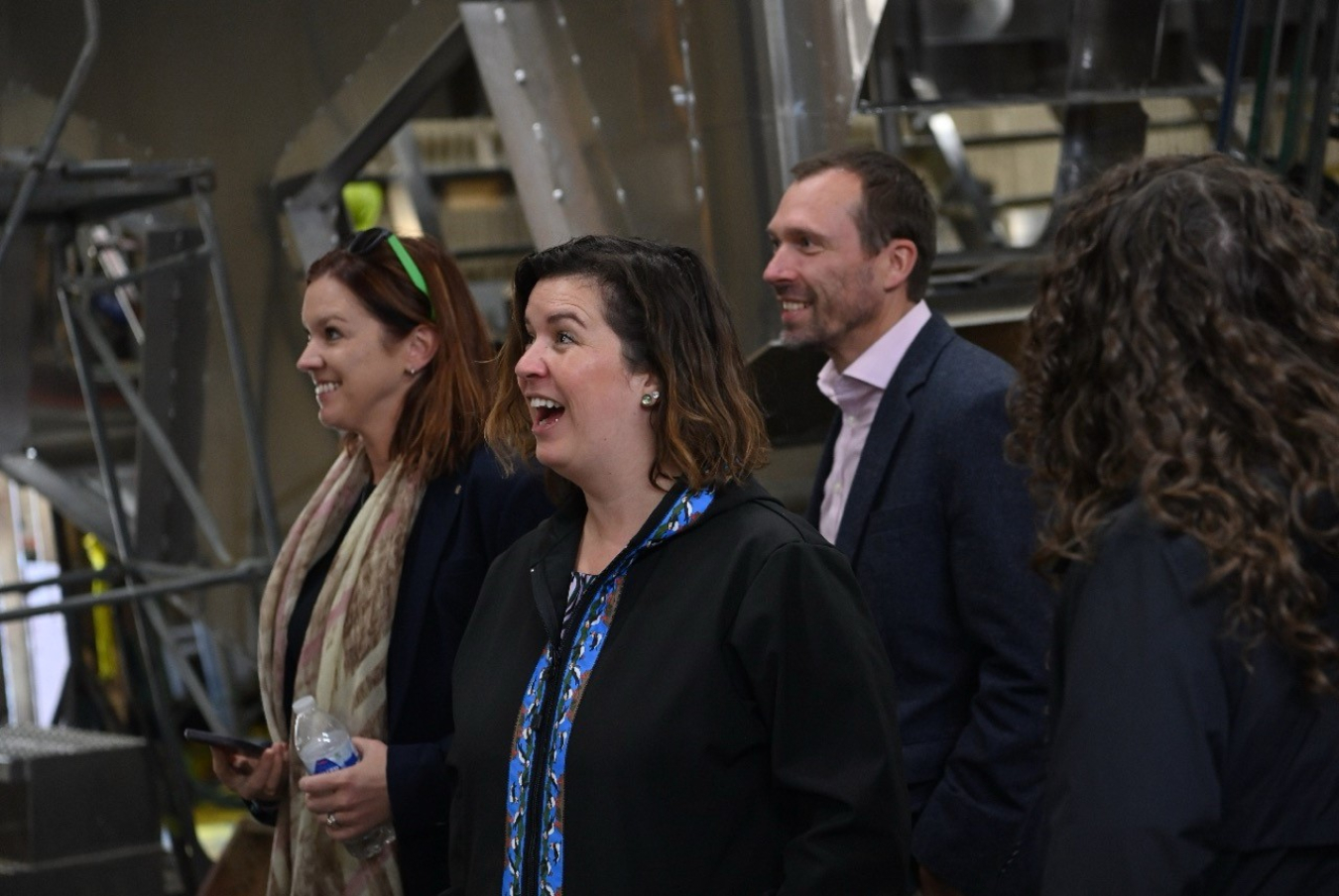 Three people standing in a group reacting with excitement and surprise.