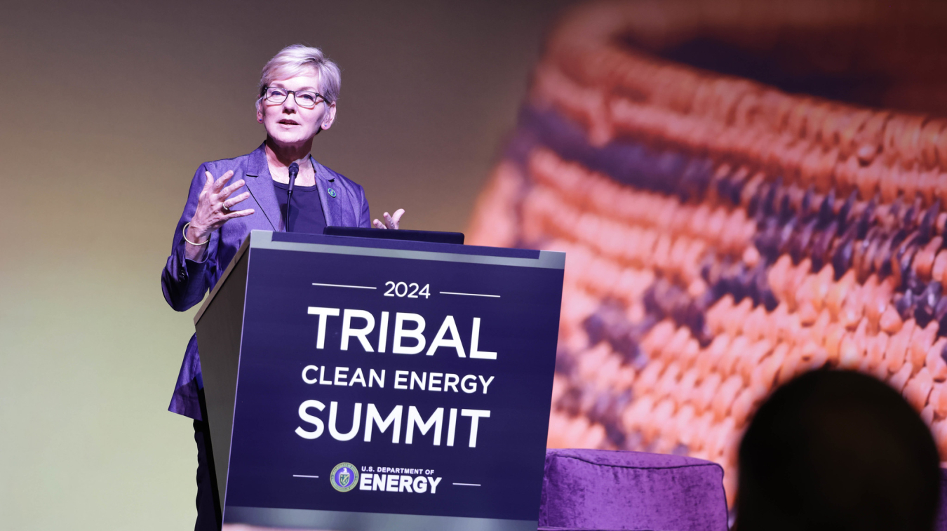 Secretary Granholm stands behind a podium at the DOE 2024 Tribal Clean Energy Summit.