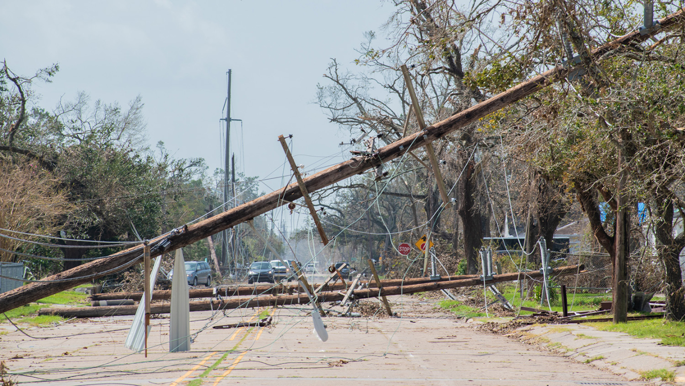 Power lines and poles lying over a street after a storm.