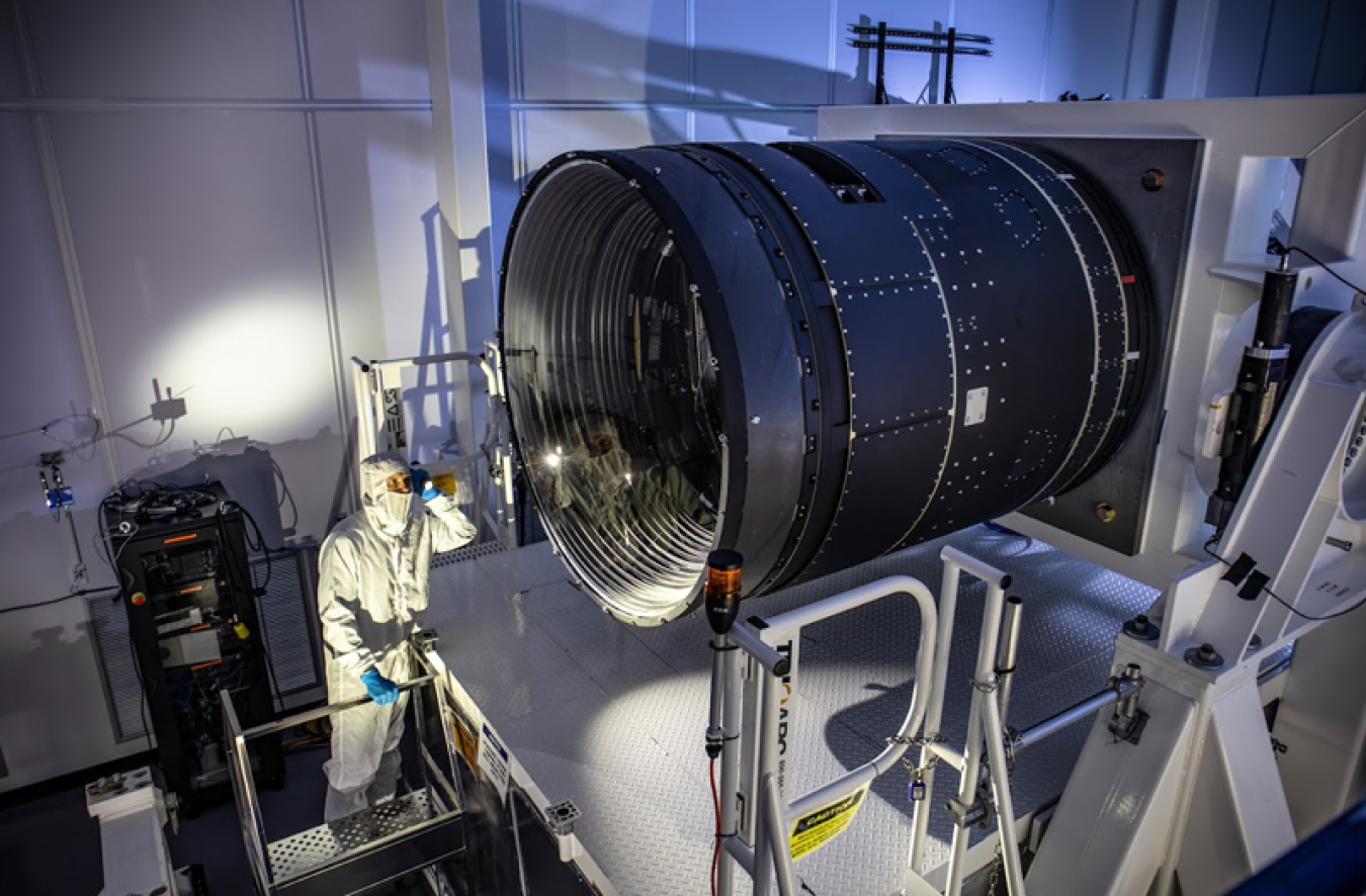 LSST Camera Deputy Project Manager Travis Lange shines a flashlight into the LSST Camera, a massive camera the size of a small car.