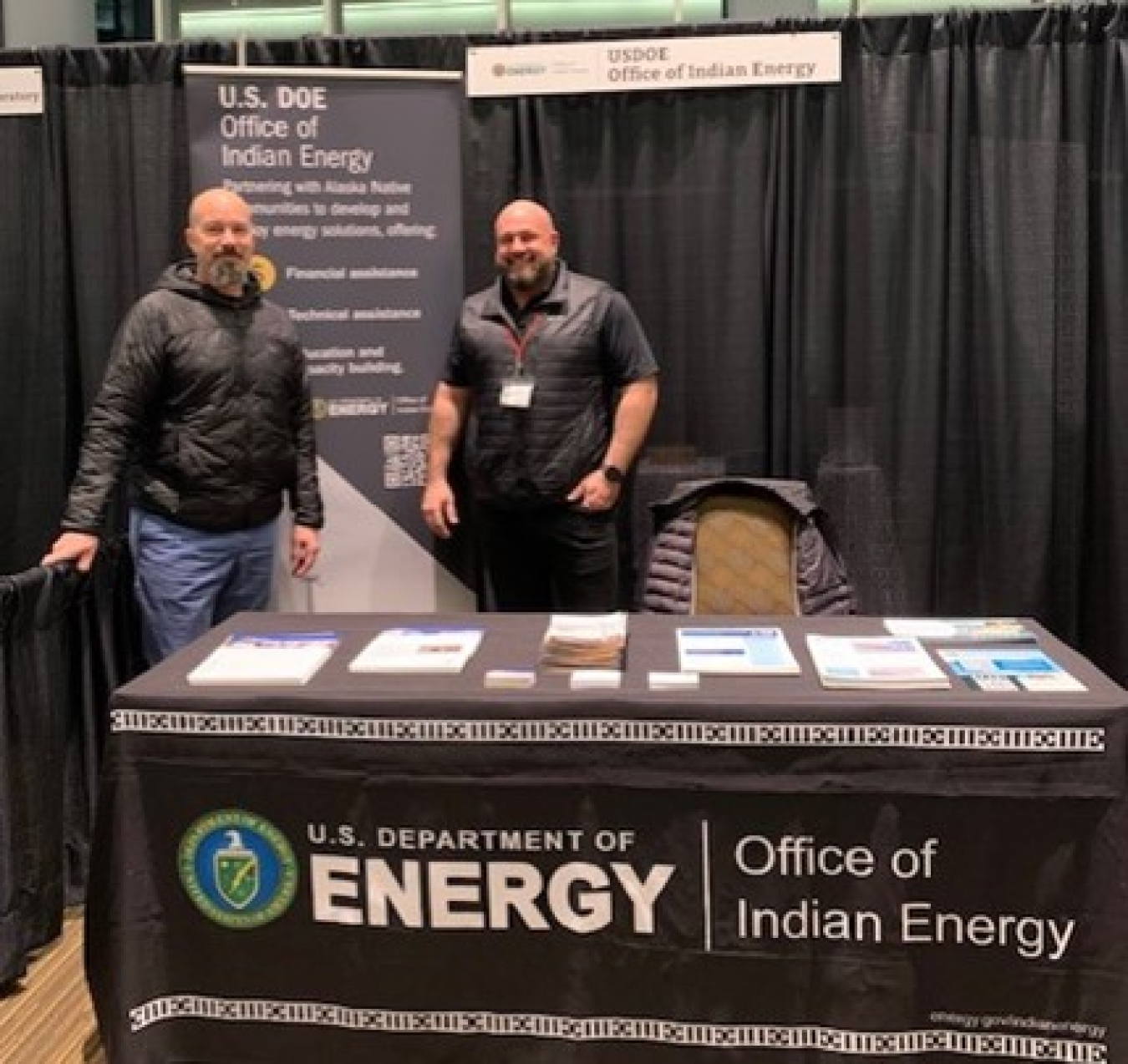 Mike Stevenson and Chris Schutte stand behind an Office of Indian Energy conference table.