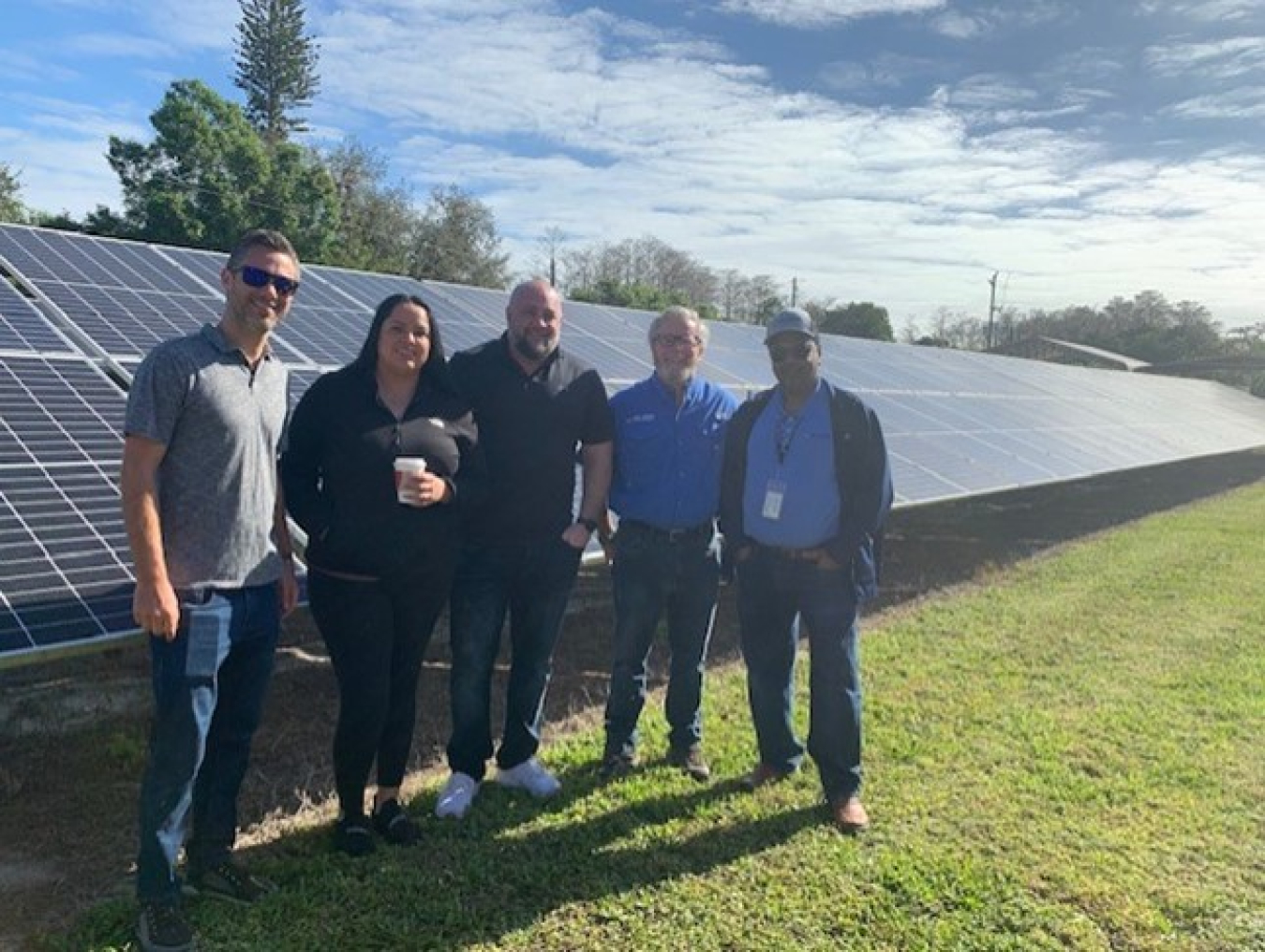 A small group poses by a solar panel.