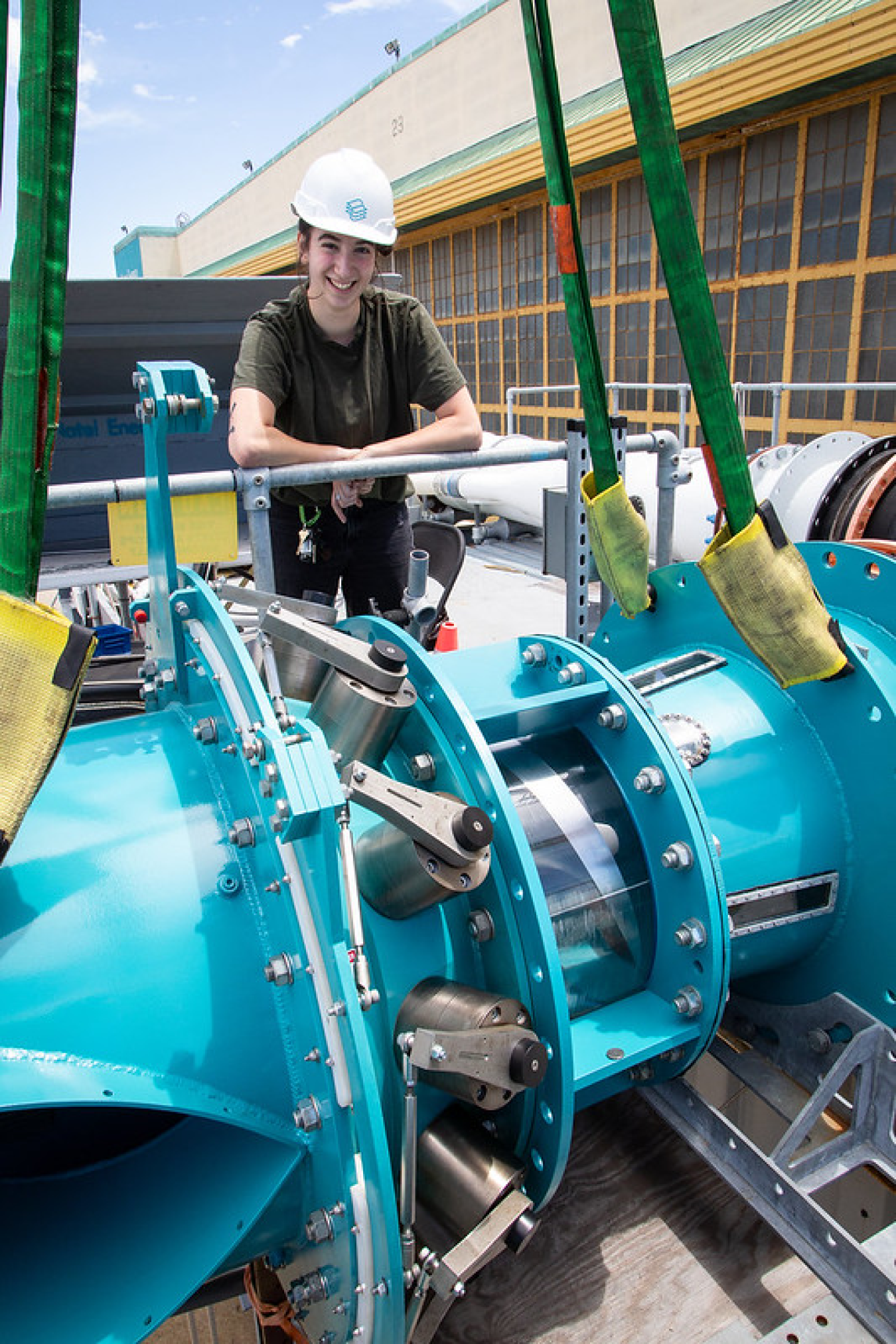 A person stands behind a section of a turquoise blue turbine.