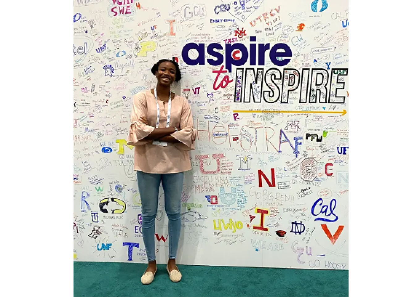 Pamela Miceus standing next to a wall of text. Largest text says "aspire to INSPIRE"