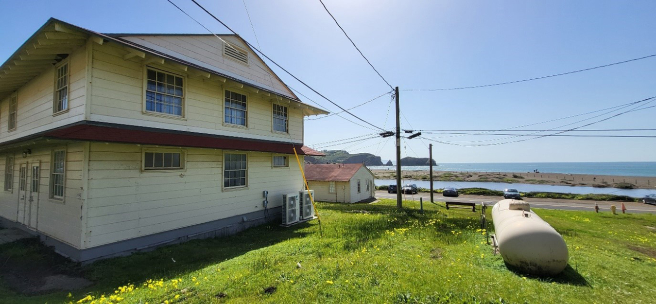 Two-story barracks building with heat pumps outside, with the ocean in the background.