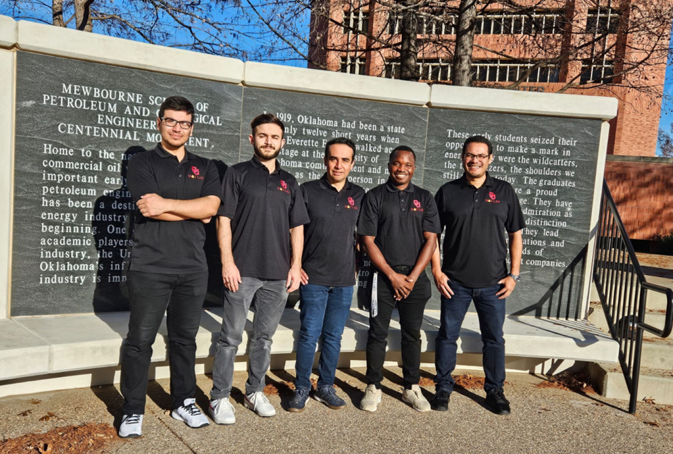 Several people in black shirts standing in front of a large monument on a university campus