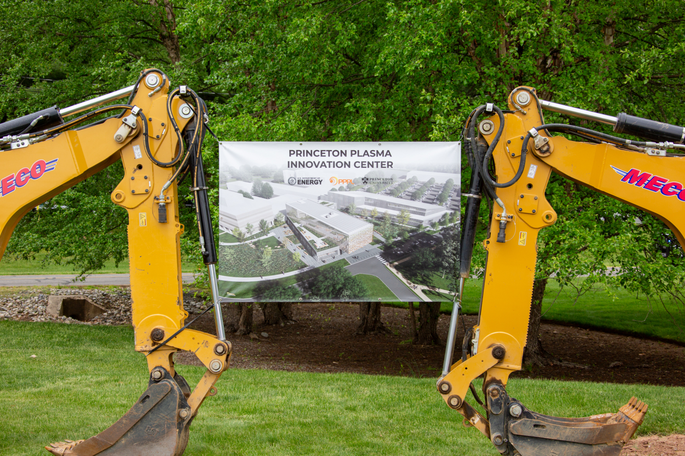 Two yellow backhoes with a sign reading Princeton Plasma Innovation Center hung between them.