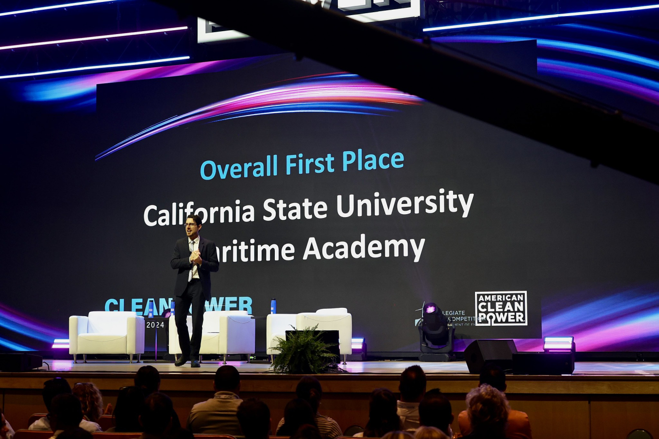 Man in suit on stage in front of audience, backdrop taht says "California State University Maritime Academy"