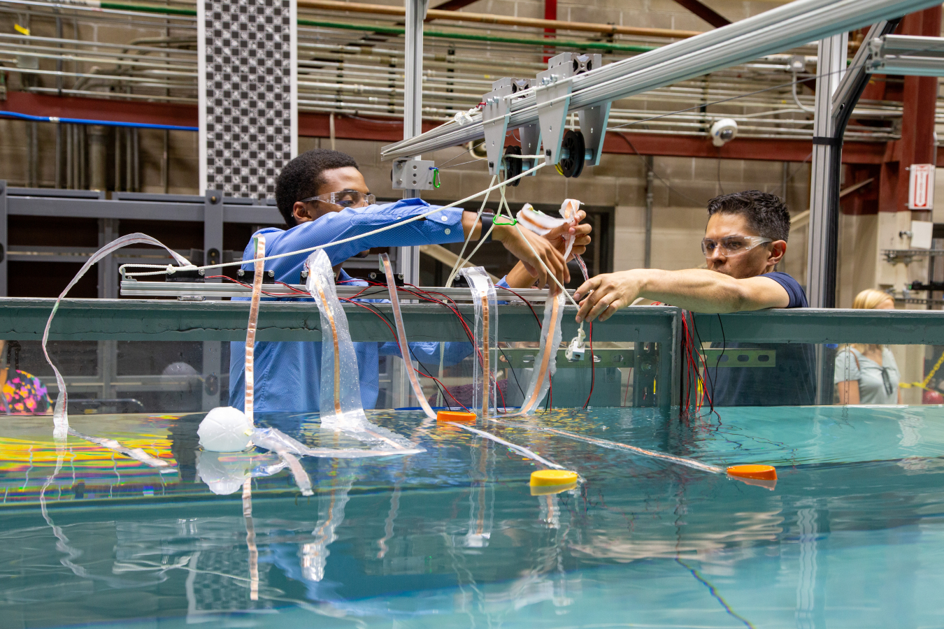 Andrew Simms and another researcher move wires next to a wave tank