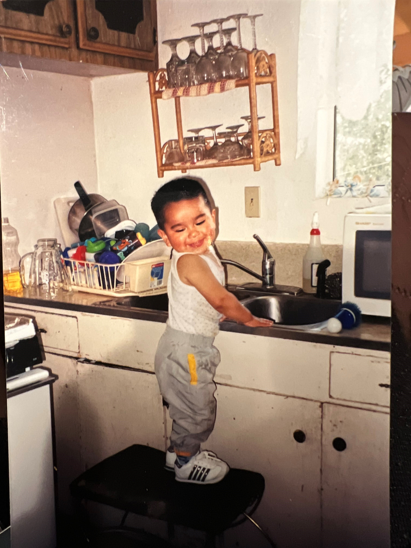 Francisco Aguirre as a toddler standing on a stool by a kitchen sink