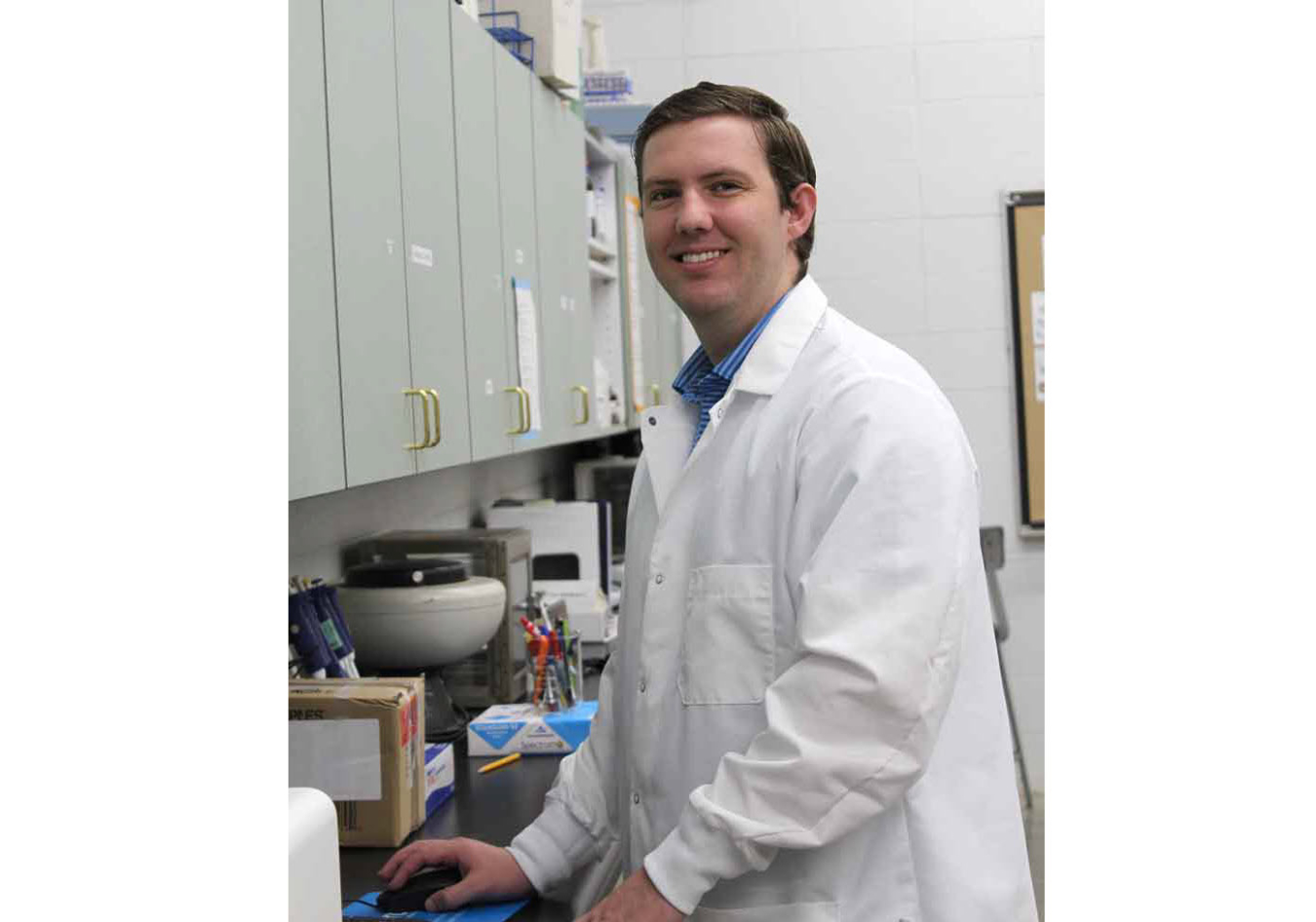 Ross Houston in a laboratory setting wearing a white lab coat.