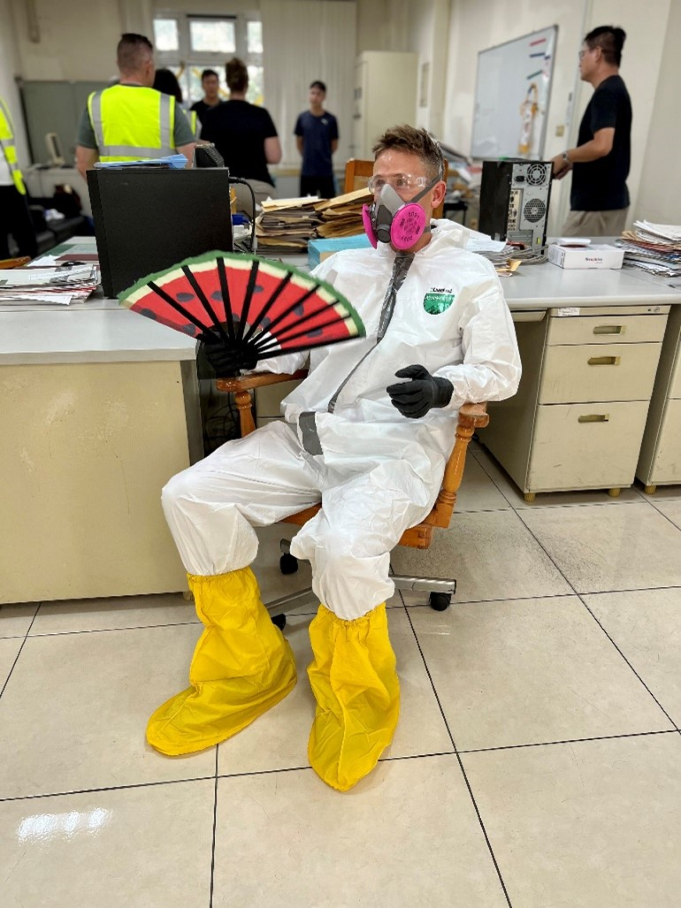 A photo of Stratz fully decked out in PPE fanning himself with a large hand fan.