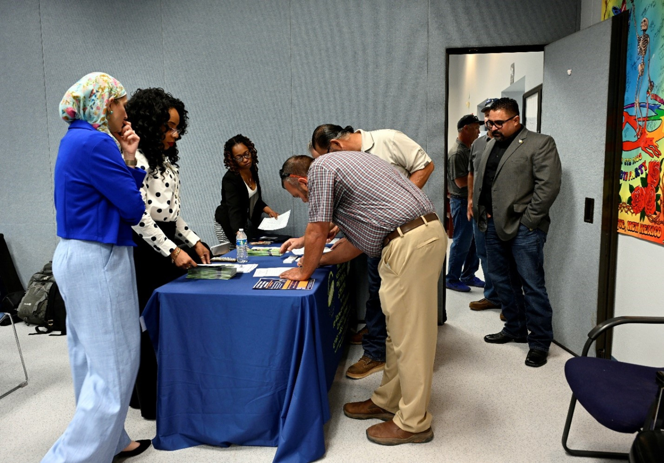 Former workers sign in at a sign in table staffed by employees. They are provided with pamphlets and other information.