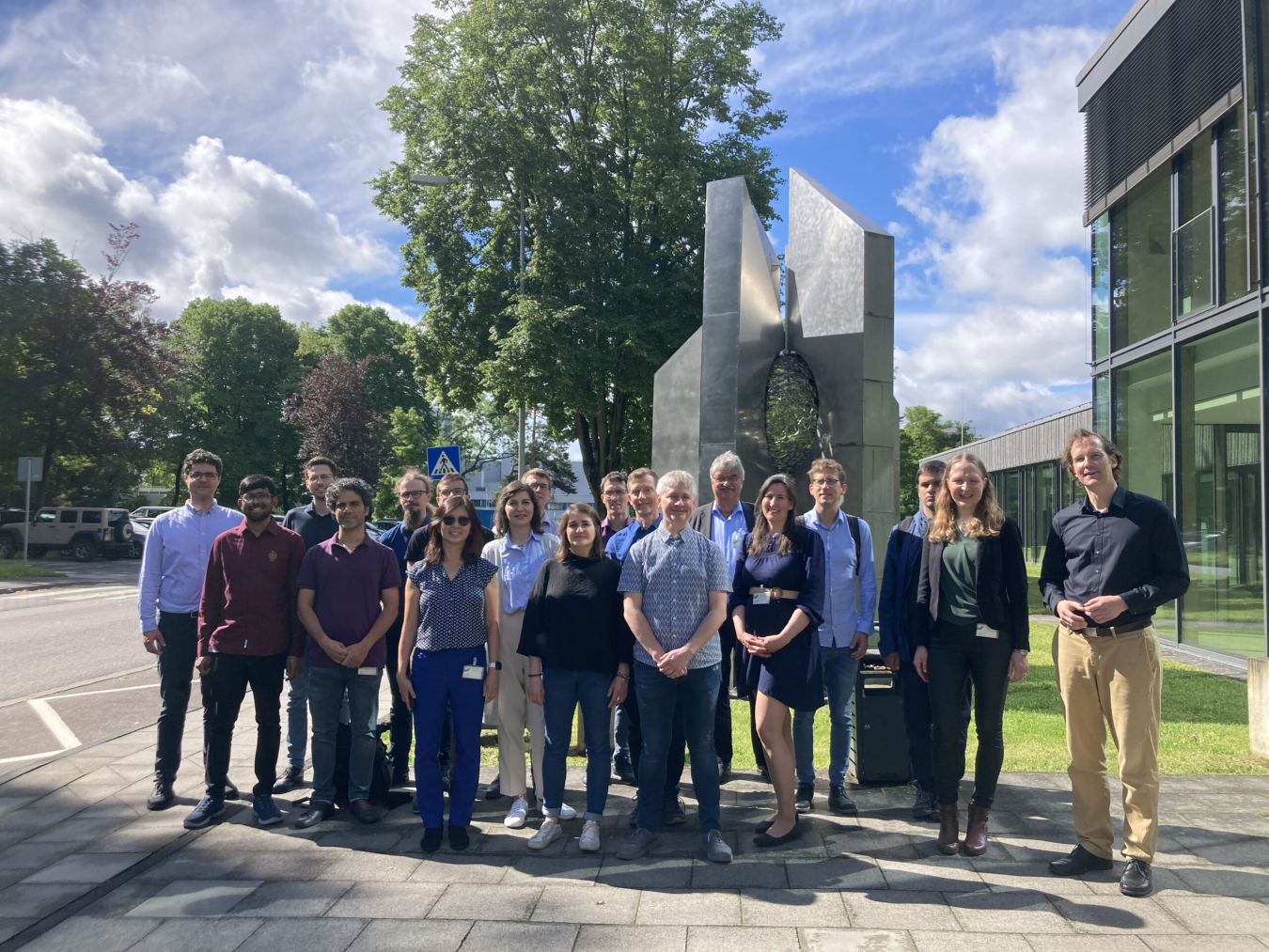 The FlowPhotoChem team smiles in front of a building at the German Aerospace Center (DLR) in Cologne, Germany.