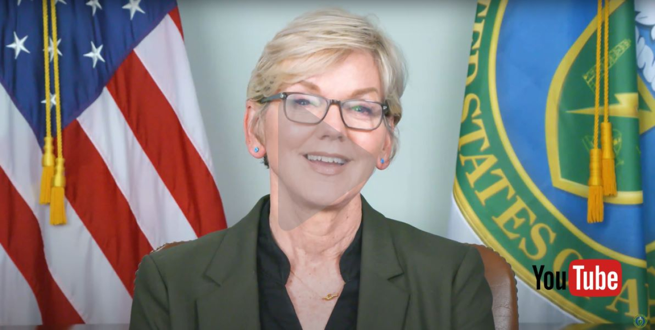 YouTube screenshot of Secretary Granholm Interview with American flag and Department of Energy flag in the background