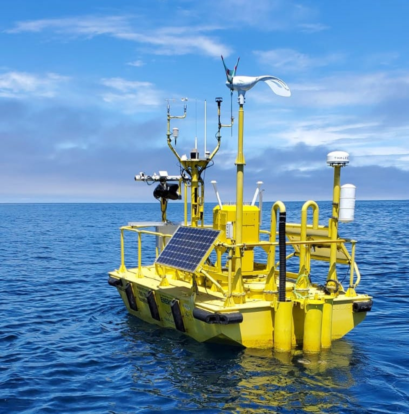 Machinery atop a buoy floating in a large body of water. 