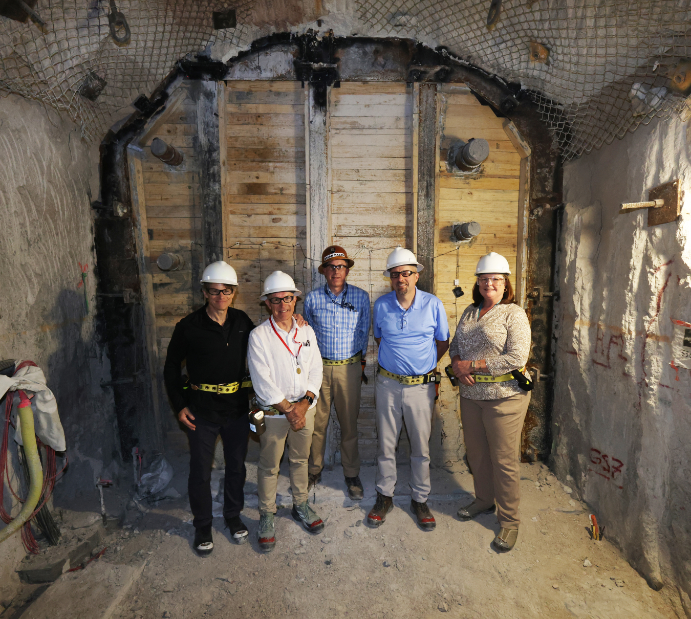 U.S. officials and Dr. Robert Floyd of CTBTO stand in front of a barrier in P-Tunnel at the Nevada National Security Site. From left, Marv Adams, Dr. Floyd, Brian Paeth (of DNN), Jeff Chamberlin, and Laura Holgate of UNVIE.