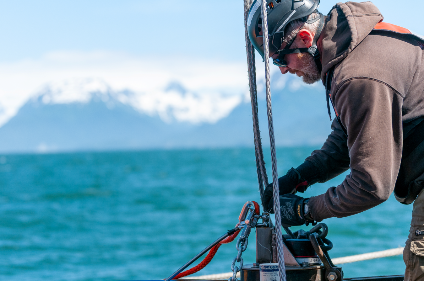 Man with hard hat and brown jacket adjusting cables at Alaska’s Cook Inlet.