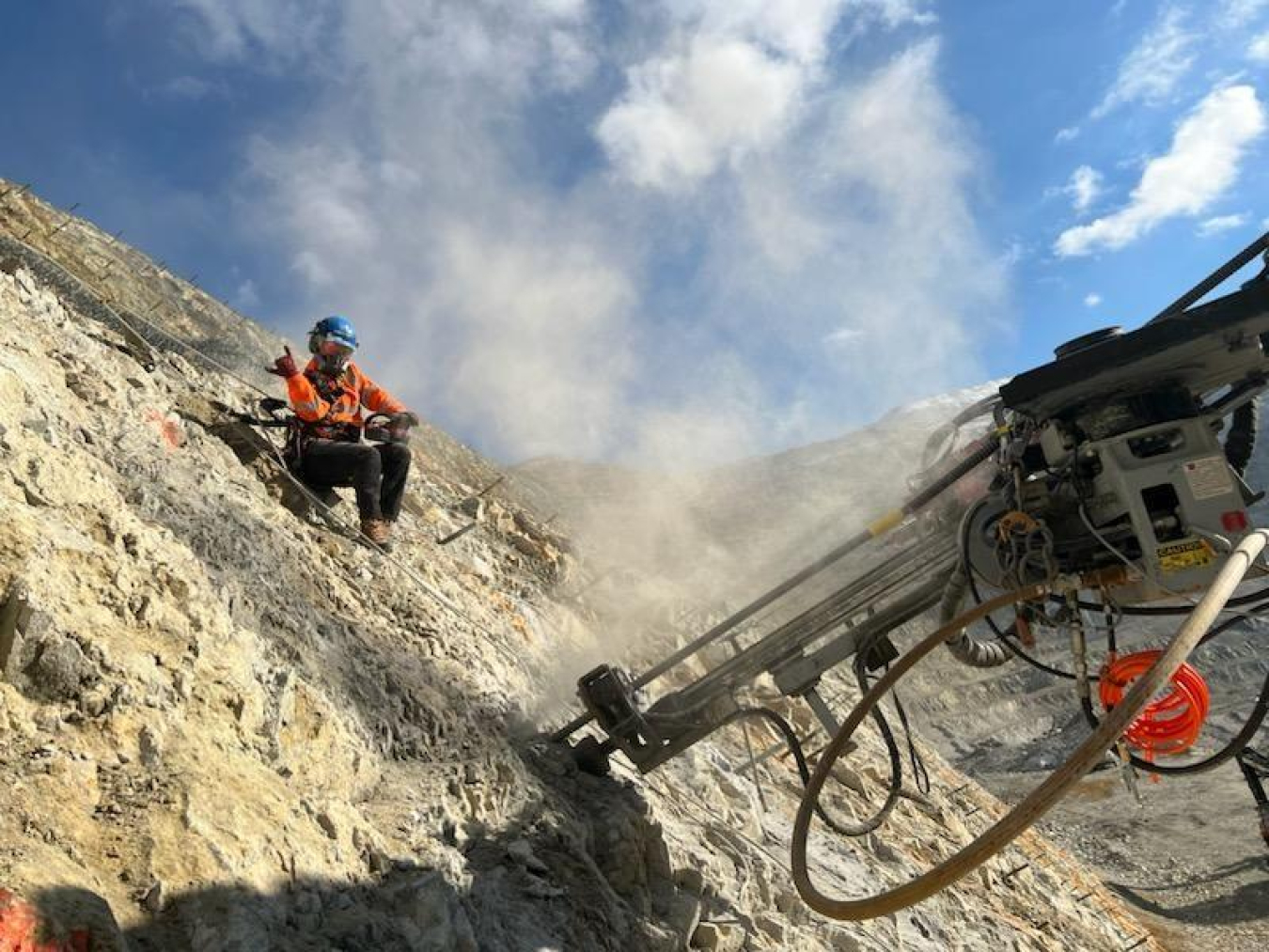 Nelson hanging from a rock wall with a drill below