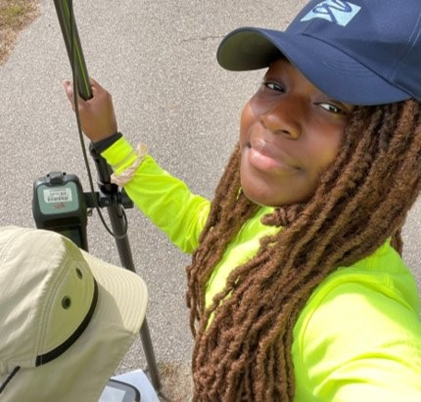 A selfie of Nazira Cisse in a baseball hat holding a fishing rod