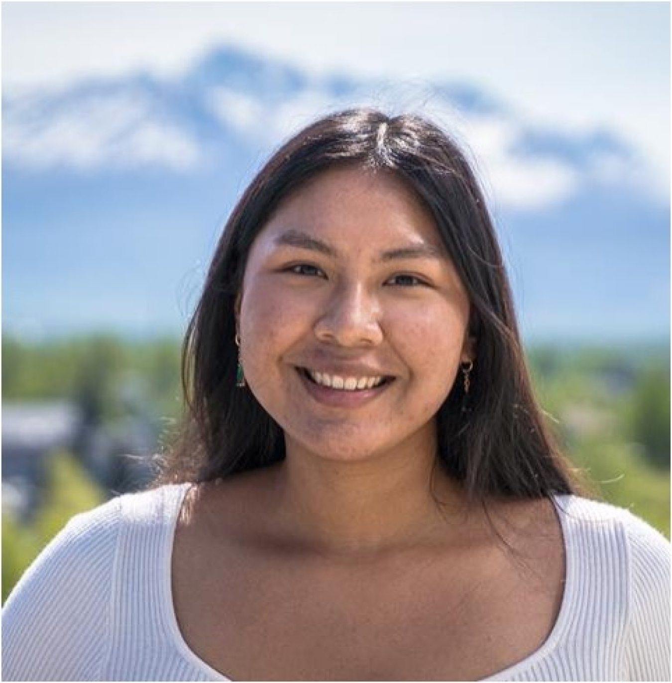 Headshot of Sherralyn Sneezer, a young woman wearing a white shirt with snowy mountains in the background