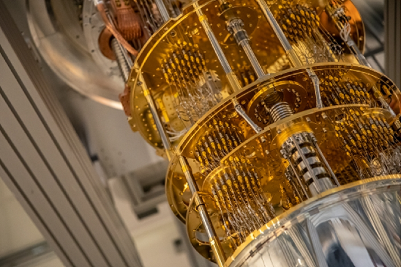 Photograph of part of a quantum computer consisting of gold plates connected by gold wires and silver tubes. 