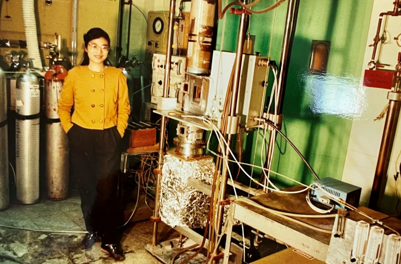 A person standing next to combustion equipment in a laboratory