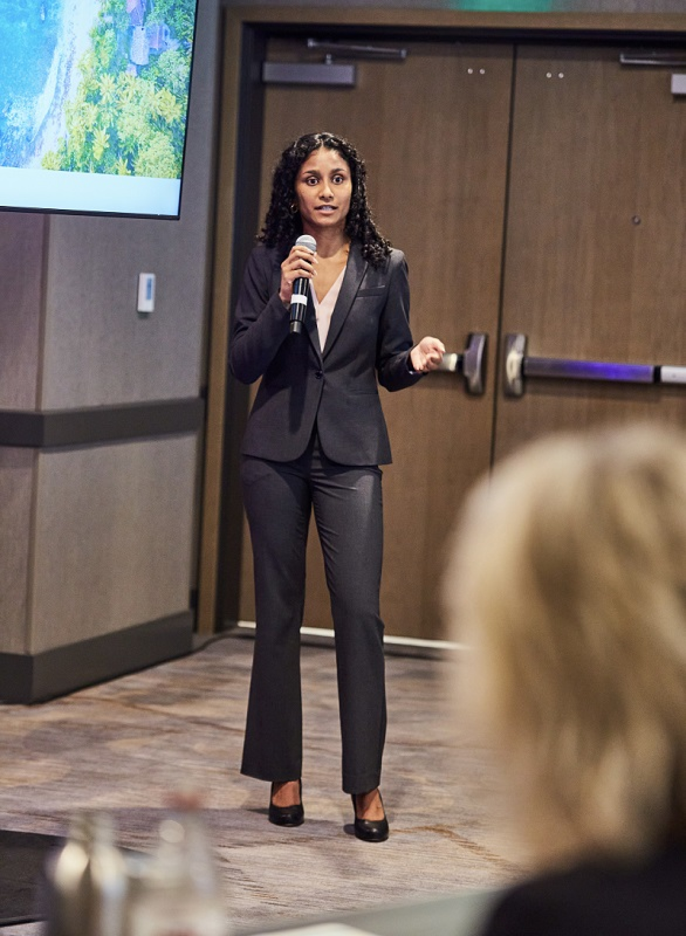 Samantha wearing a suit and speaking into a microphone