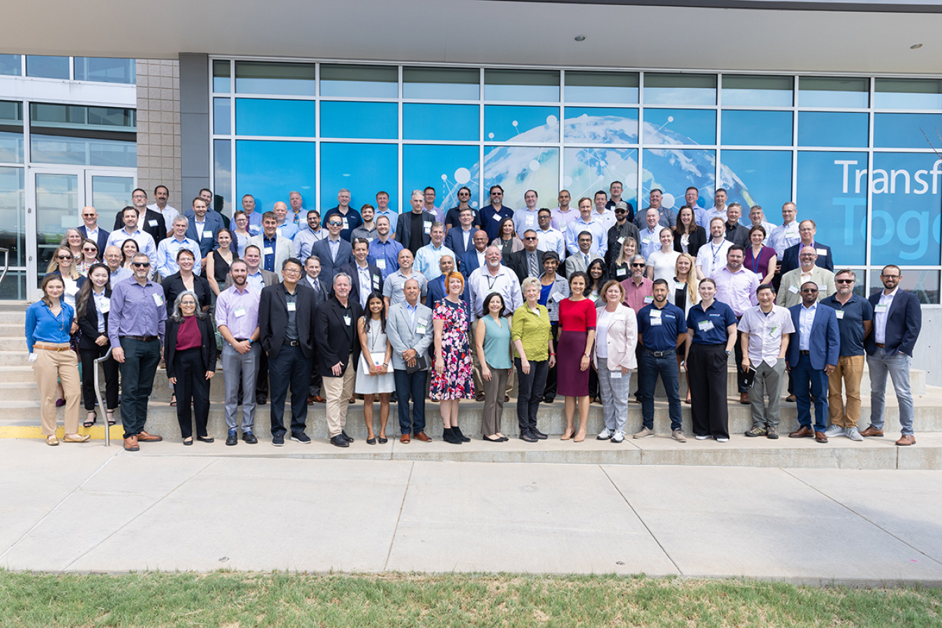 A large group of people posing for a photo outside of a building.