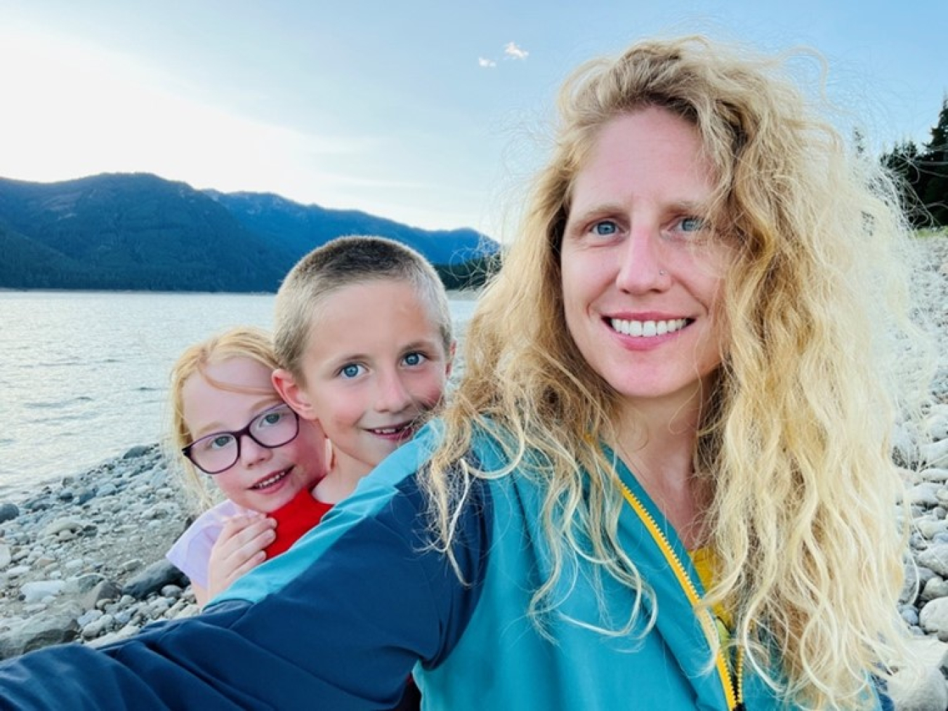 A woman takes a picture with family nearby water