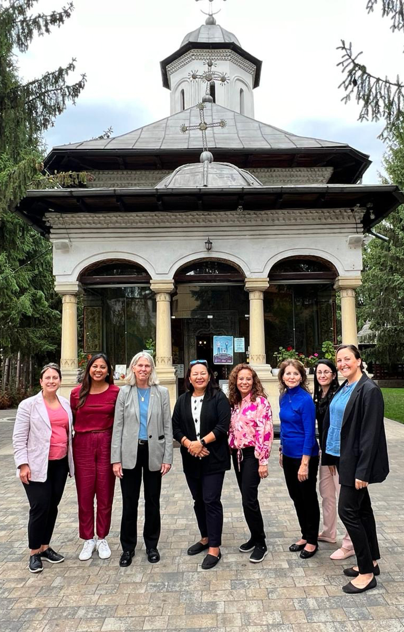 Eight women stand outside in front of a domed building.