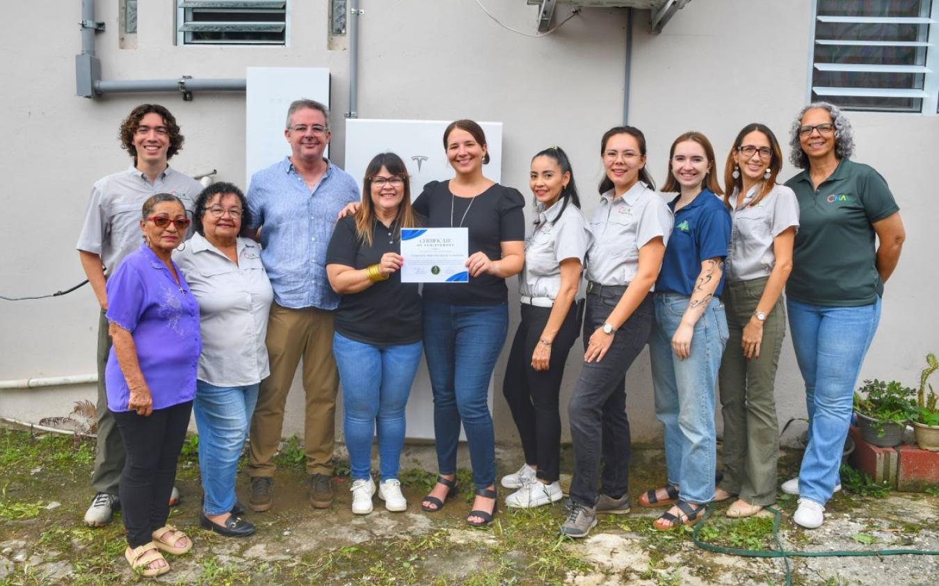 DOE’s Marisol Bonnet, the Secretary’s Advisor on Puerto Rico, and Agustin Carbó, Director of the Puerto Rico Grid Recovery and Modernization Team, present a certificate of achievement to the Cooperativa Hidroeléctrica de la Montaña, a Solar Ambassador for the Programa Acceso Solar. 