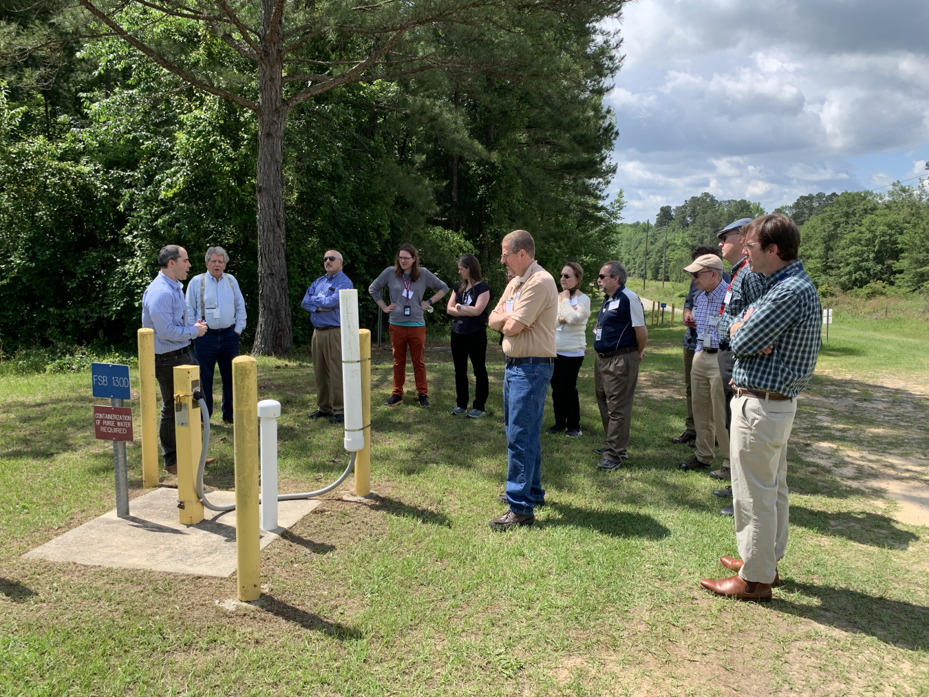 A group of individuals stand outside around a groundwater pump