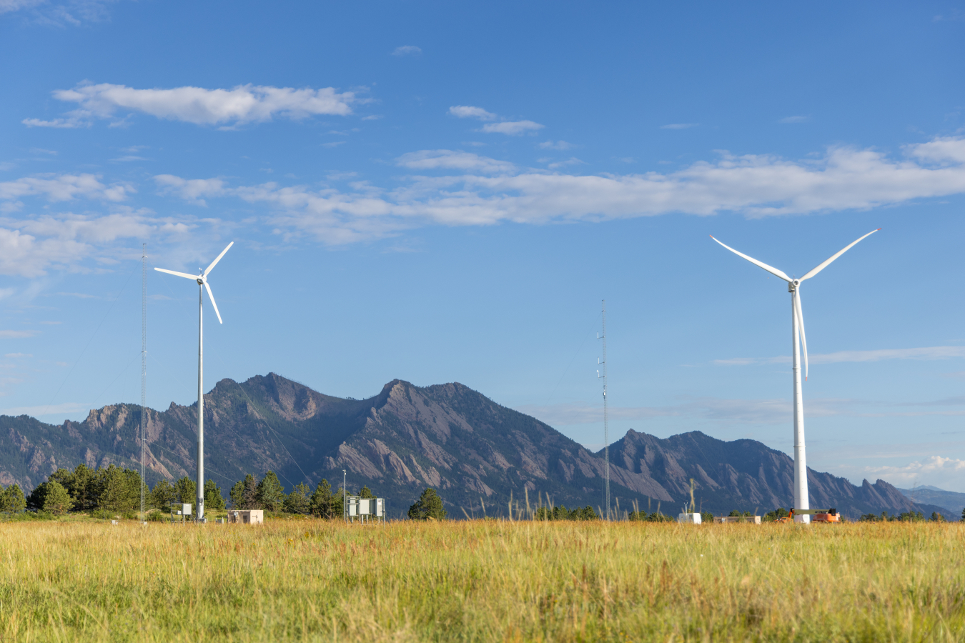 Two wind turbines in a grassy, mountainous area. 