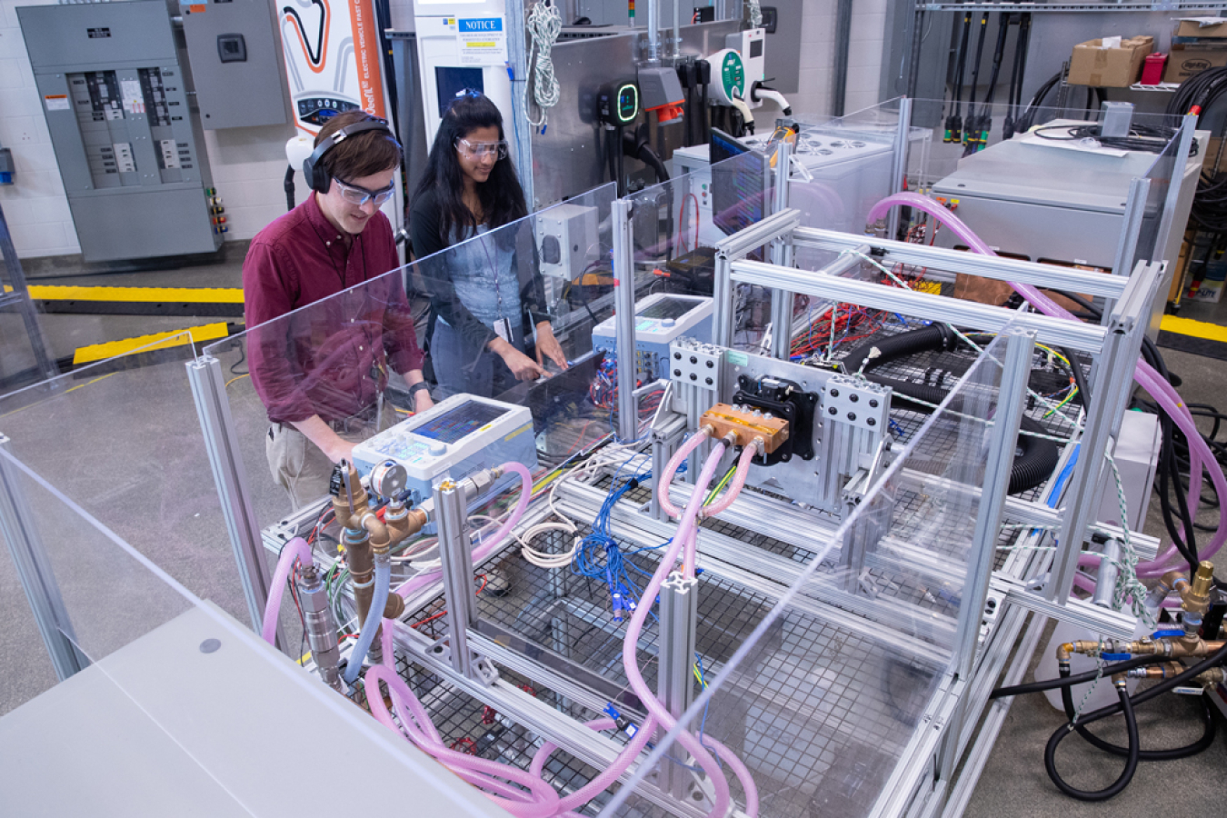 NREL researchers Isaac Tolbert and Namrata Kogalur interact with the Megawatt Charging System Thermal Evaluation Bench in a laboratory as part of a EVs@Scale Lab Consortium high-power charging pillar project.