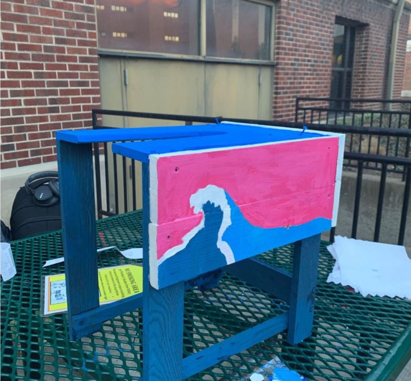 A photo containing a homemade water wheel test device with a wave painted on it.